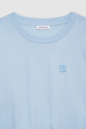 Pale blue cropped tee with framed monogram embroidery on chest and "ANINE BING" brand label at neckline.