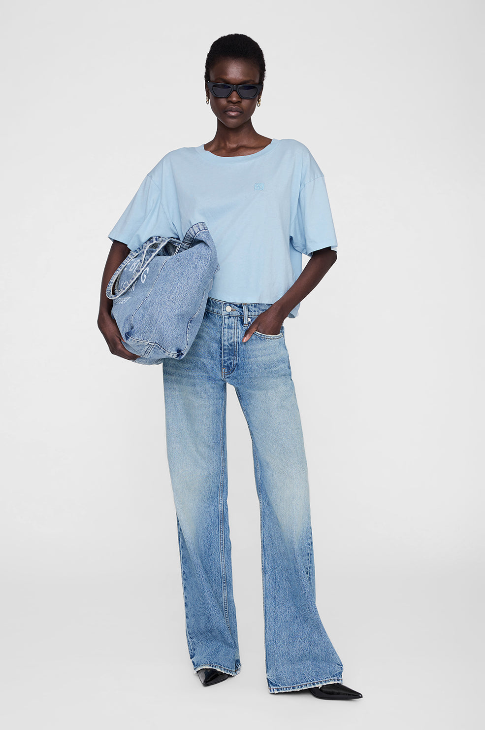 Pale blue cropped tee with framed monogram detail, worn with blue jeans.