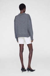 Ecru shorts paired with a gray crewneck sweatshirt and black kitten heels.