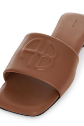 Cognac leather slide with embossed logo detail and black sole.