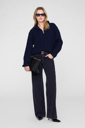 Midnight blue ribbed sweater with quarter-zip collar worn with dark jeans and black accessories.