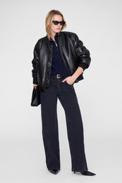 Midnight blue ribbed sweater worn under a black leather jacket with dark jeans.