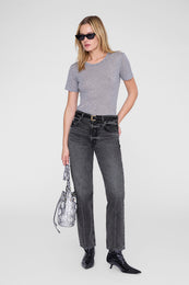 Woman wearing a grey short-sleeve crew neck tee with black sunglasses, dark jeans, and black boots.