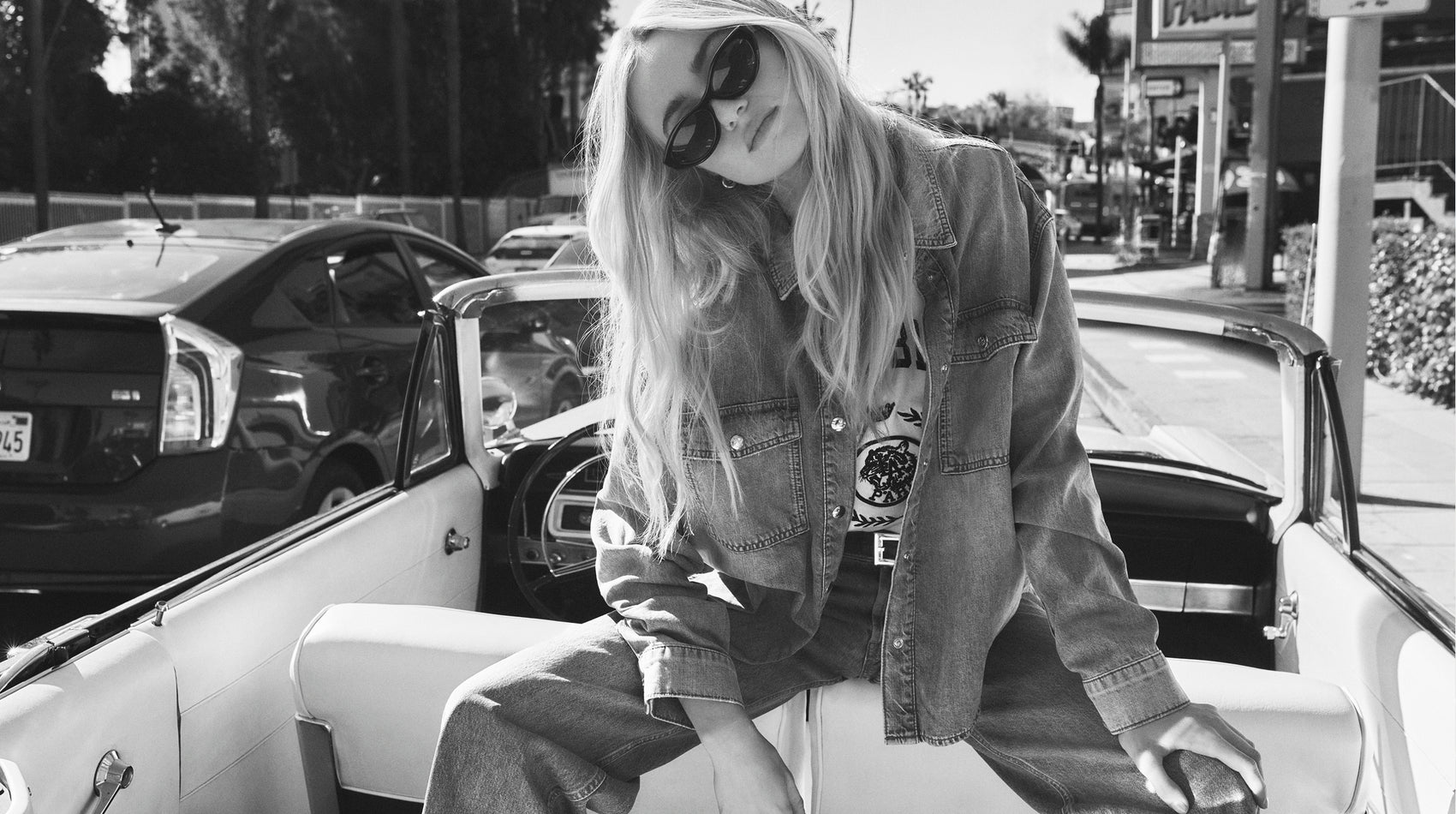 Person sitting in the back of a vintage car with a casual style.